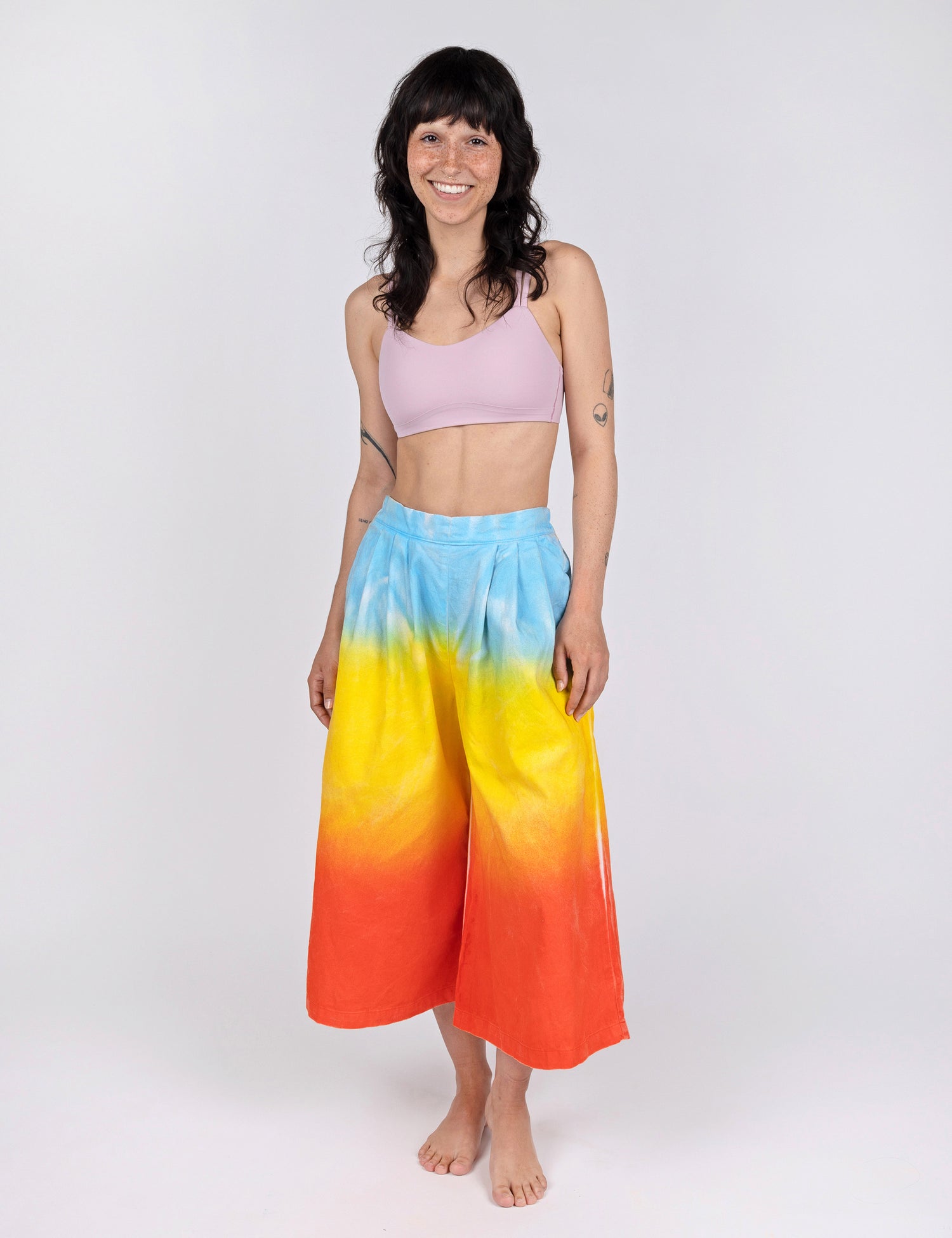 woman wearing culotte pants in gradient design of blue yellow and red orange.