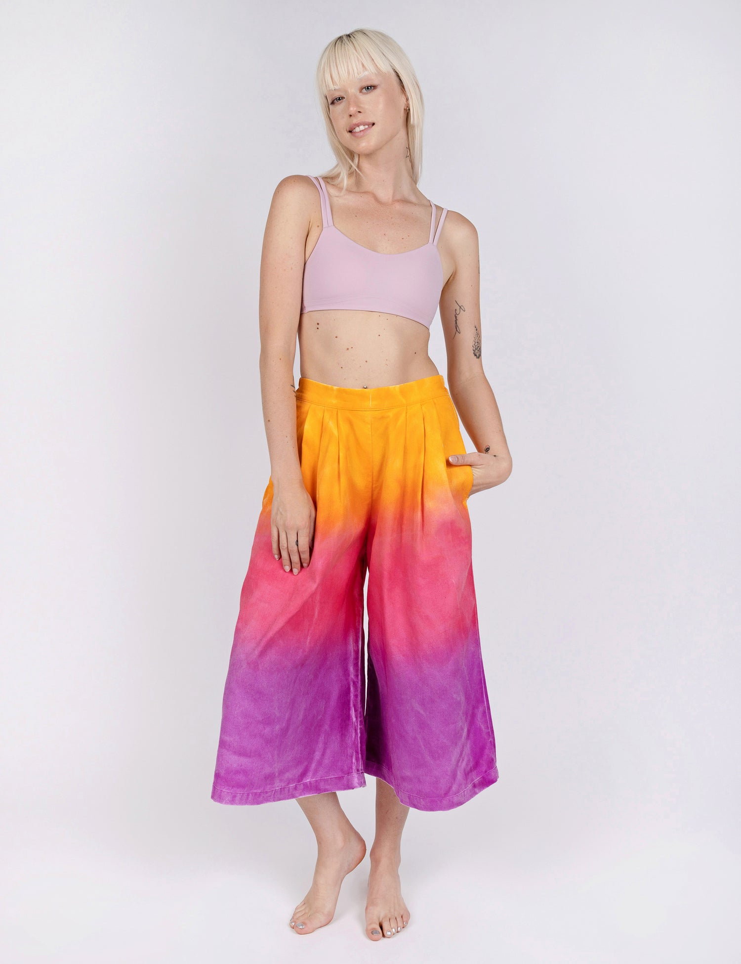 woman wearing culotte pants in gradient design of yellow pink and purple.