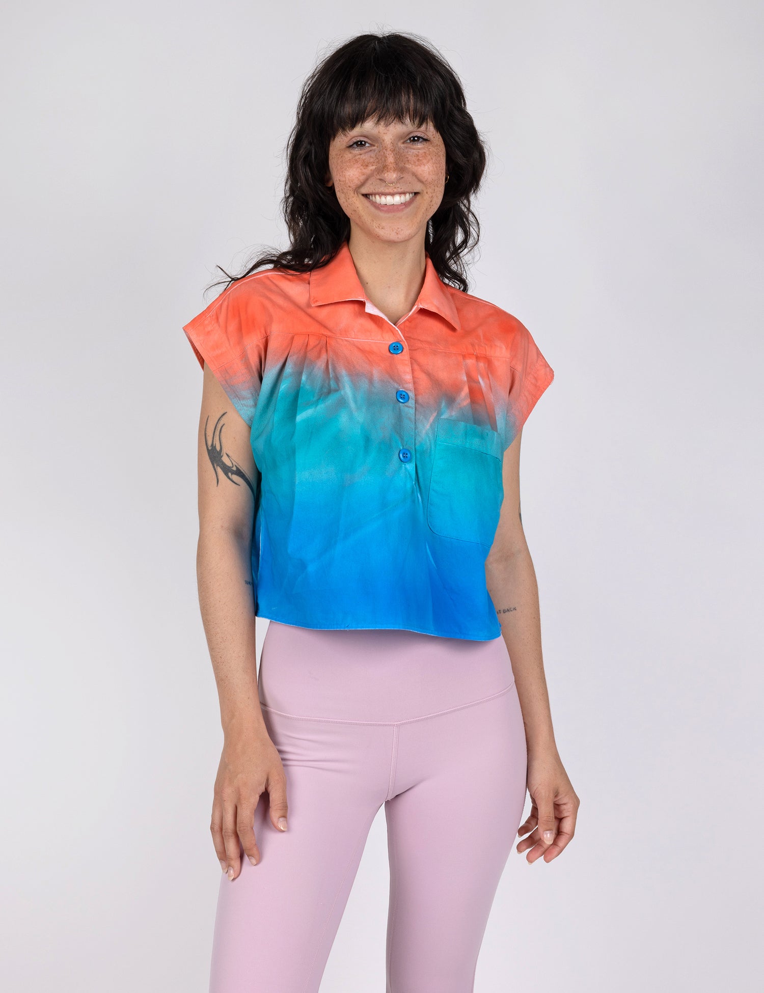 woman wearing a cropped half button down shirt in gradient designs of red teal and blue