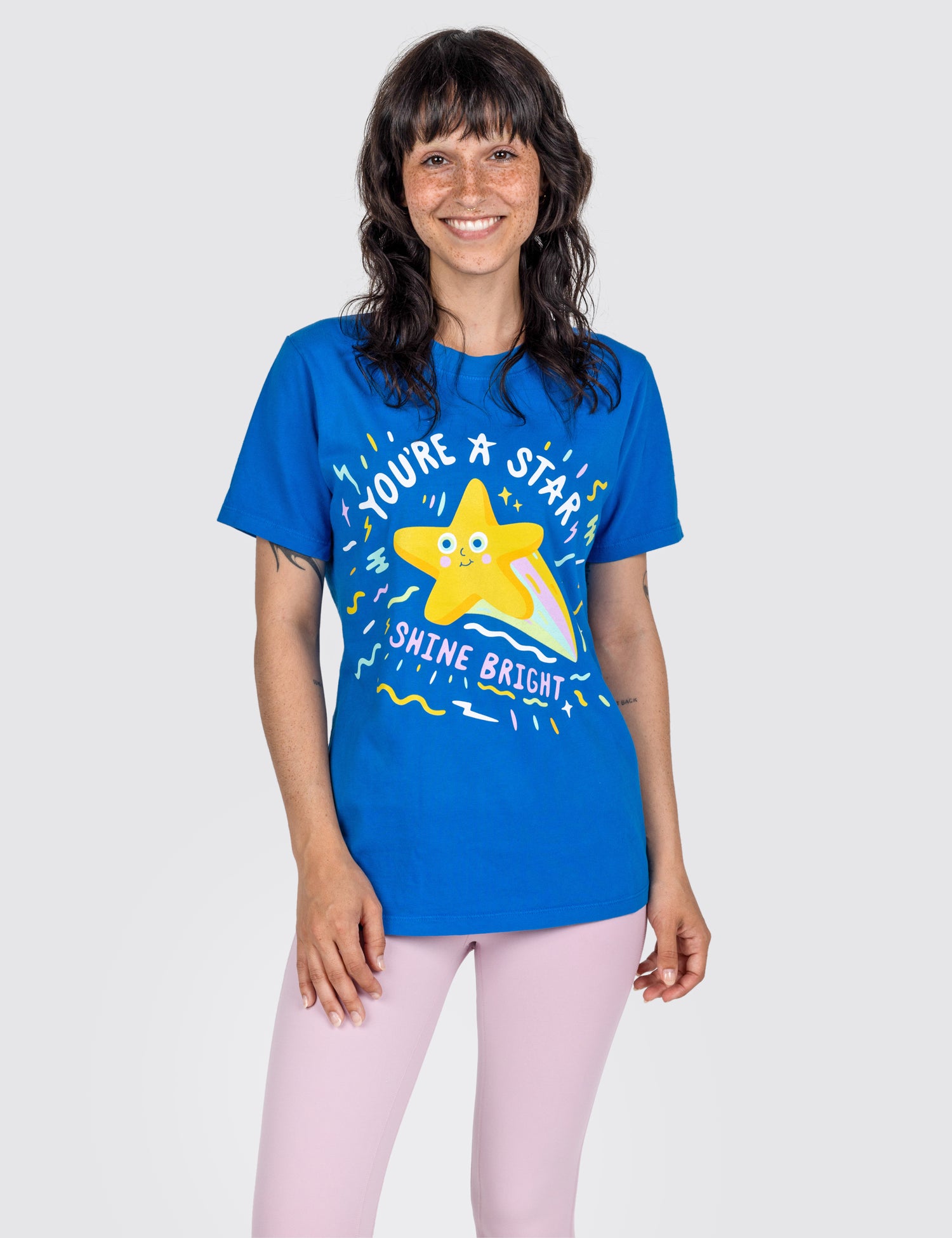 Woman wearing a blue T-shirt with screen print design on it saying the words you're a star shine bright