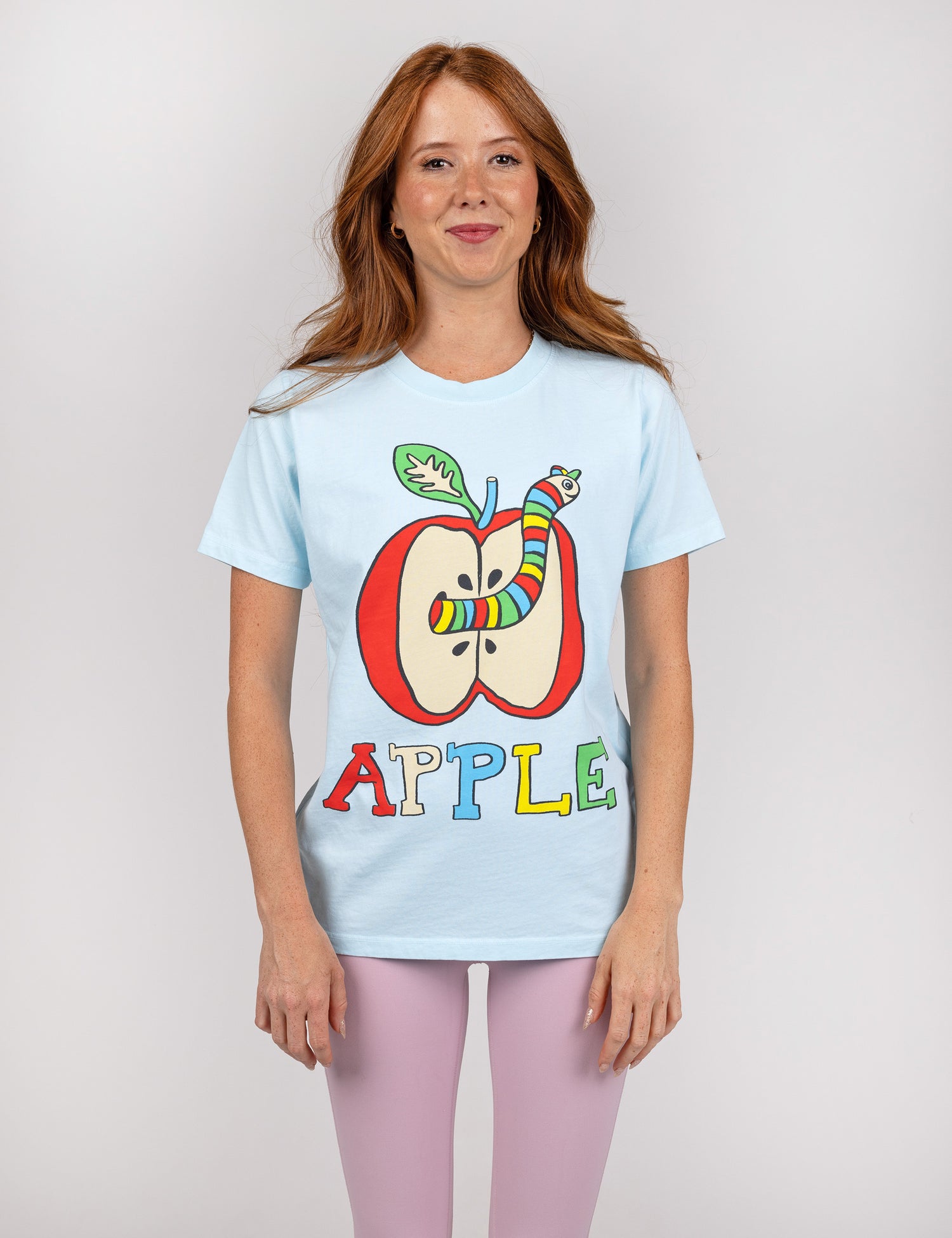 woman wearing light blue shirt with an apple and worm design in the center.