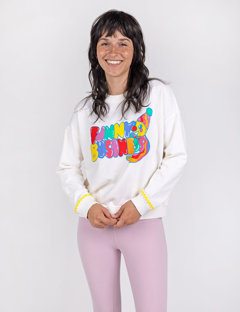 Woman wearing a white crop crew sweatshirt with colorful letters and design