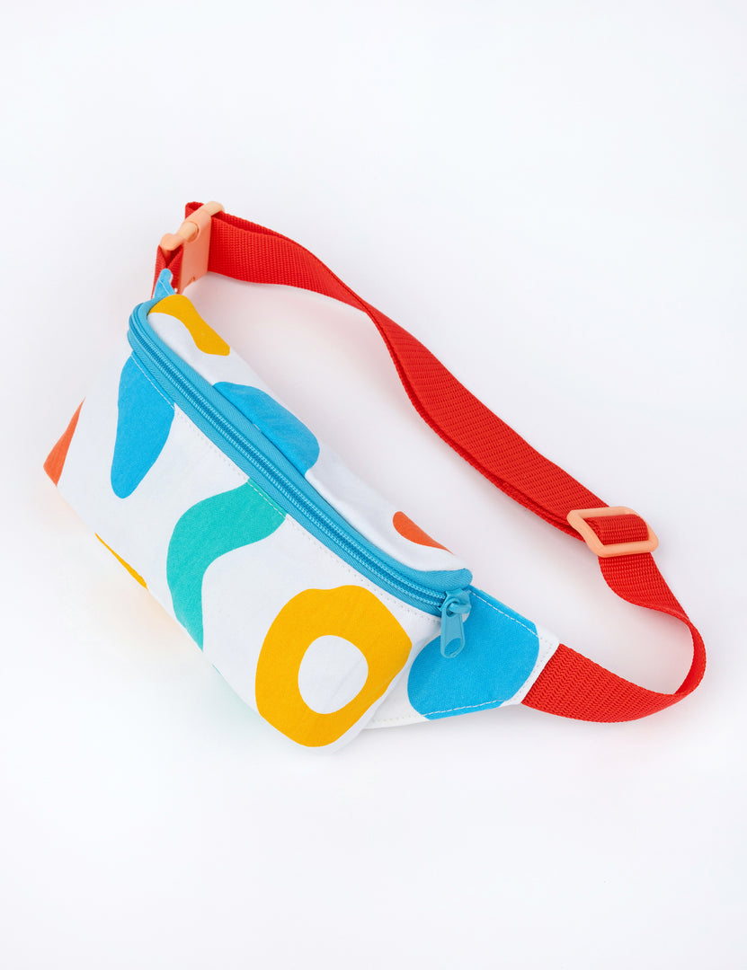 small white fanny pack with colorful designs and red strap