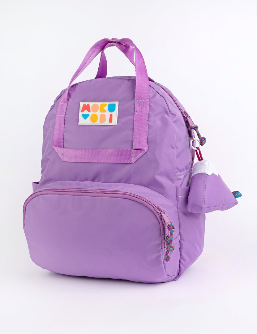 A solid colored backpack with a mountain keychain accessory