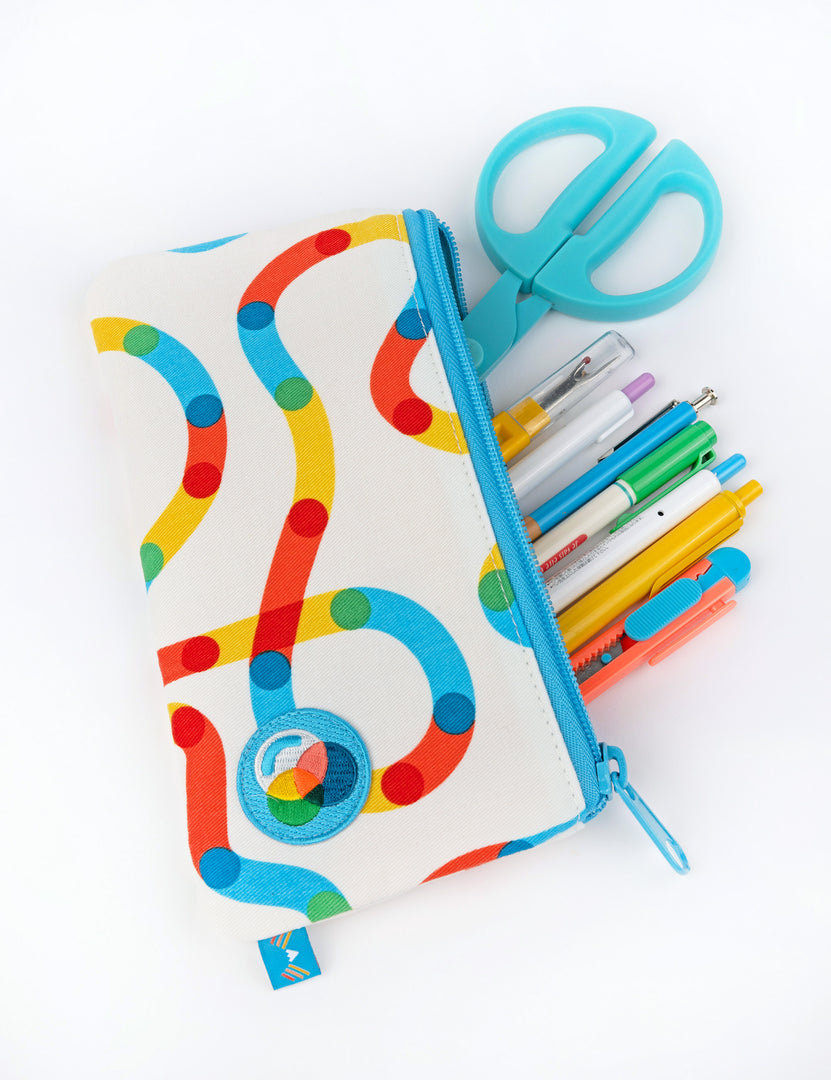 A white pencil pouch with colorful squiggles and a prism patch on the bottom corner
