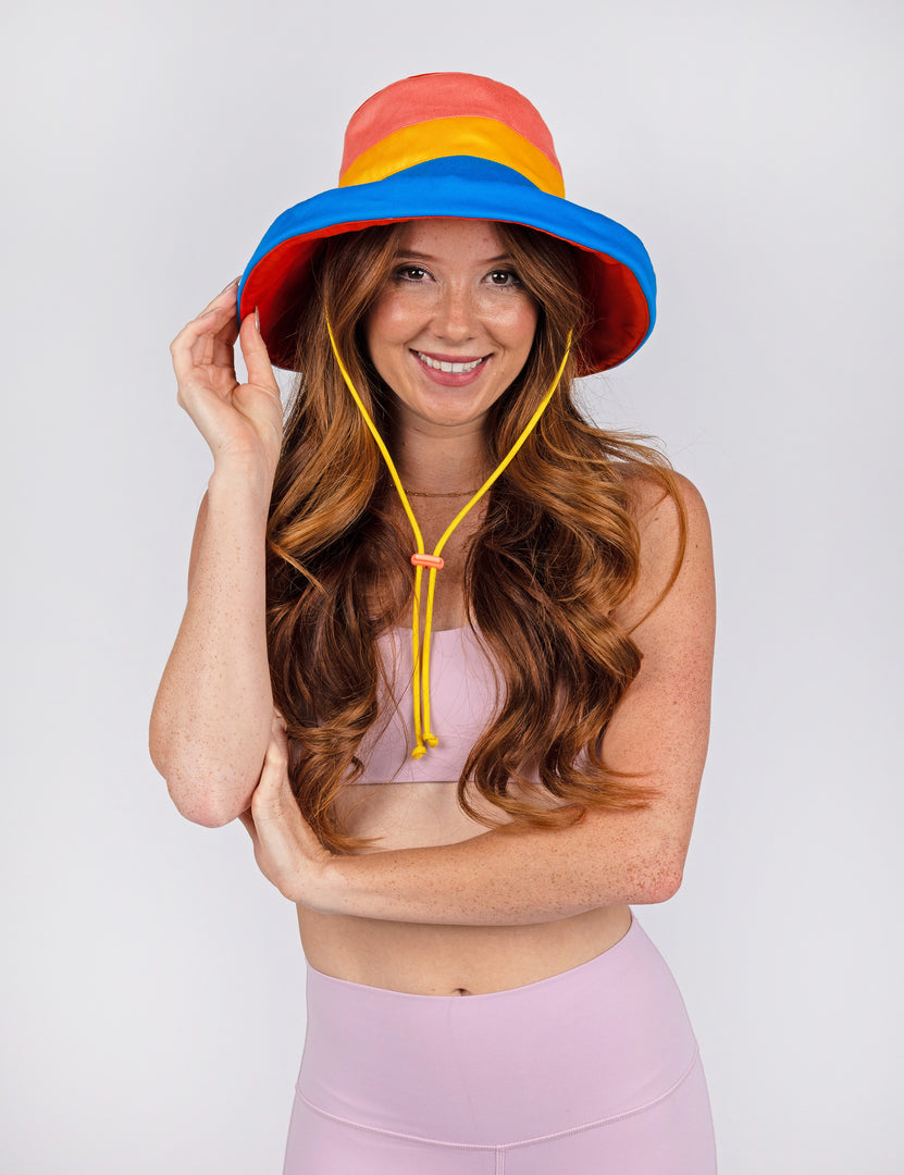woman wearing bucket style sunhat with red coral blue and yellow.