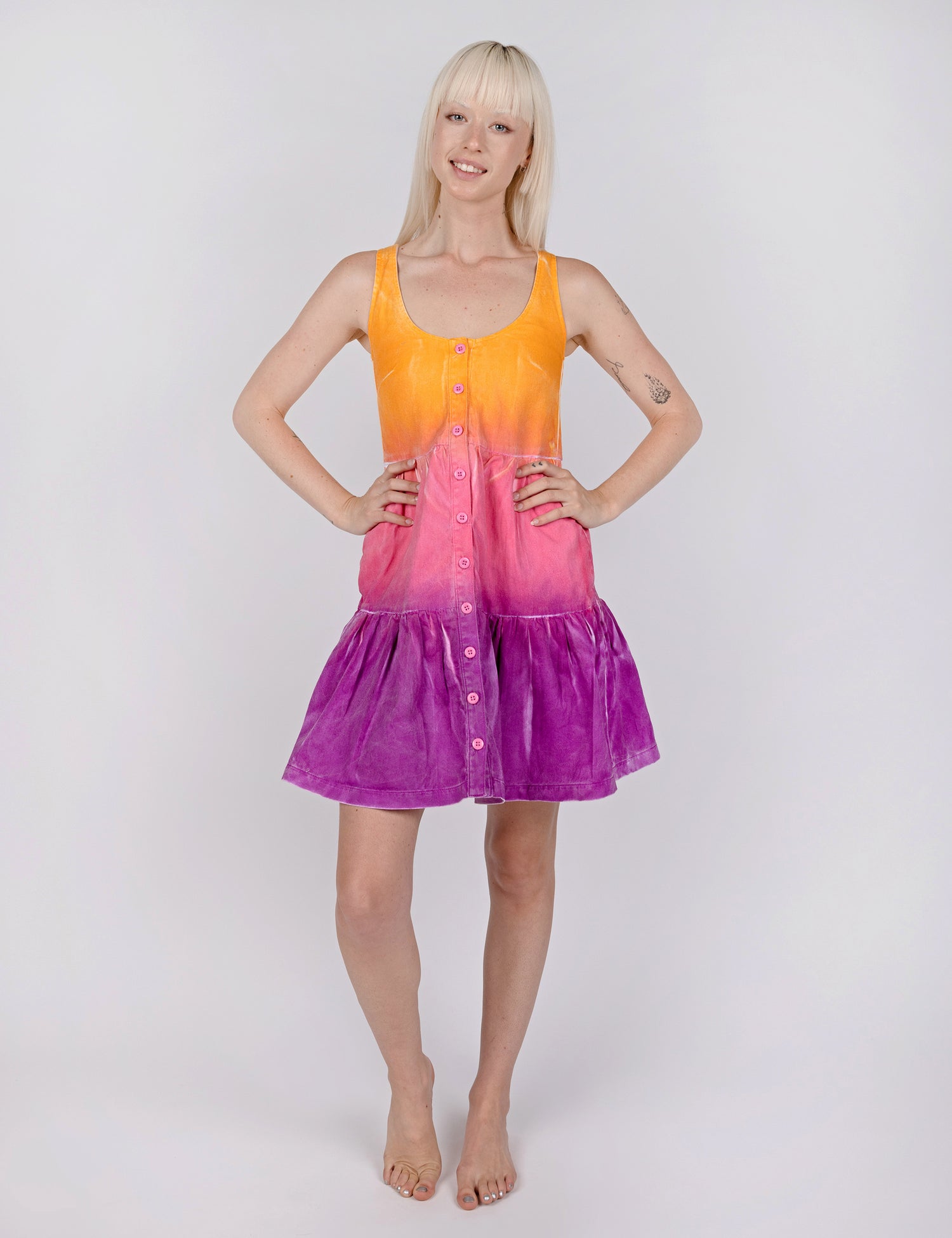 woman wearing tier style dress in gradient design of yellow pink and purple