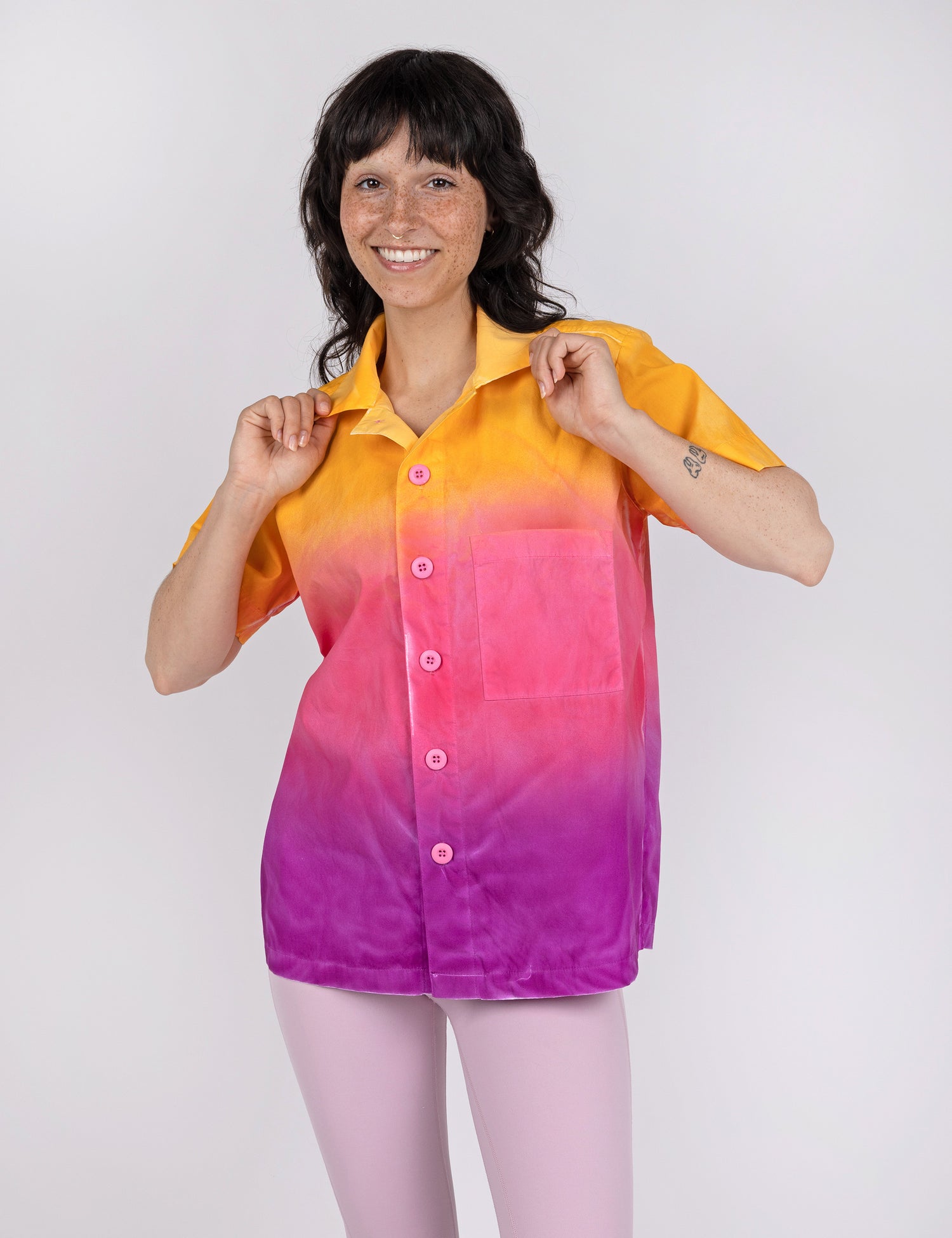 woman wearing a button down shirt in gradient designs of yellow pink and purple.