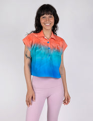 woman wearing a cropped half button down shirt in gradient designs of red teal and blue