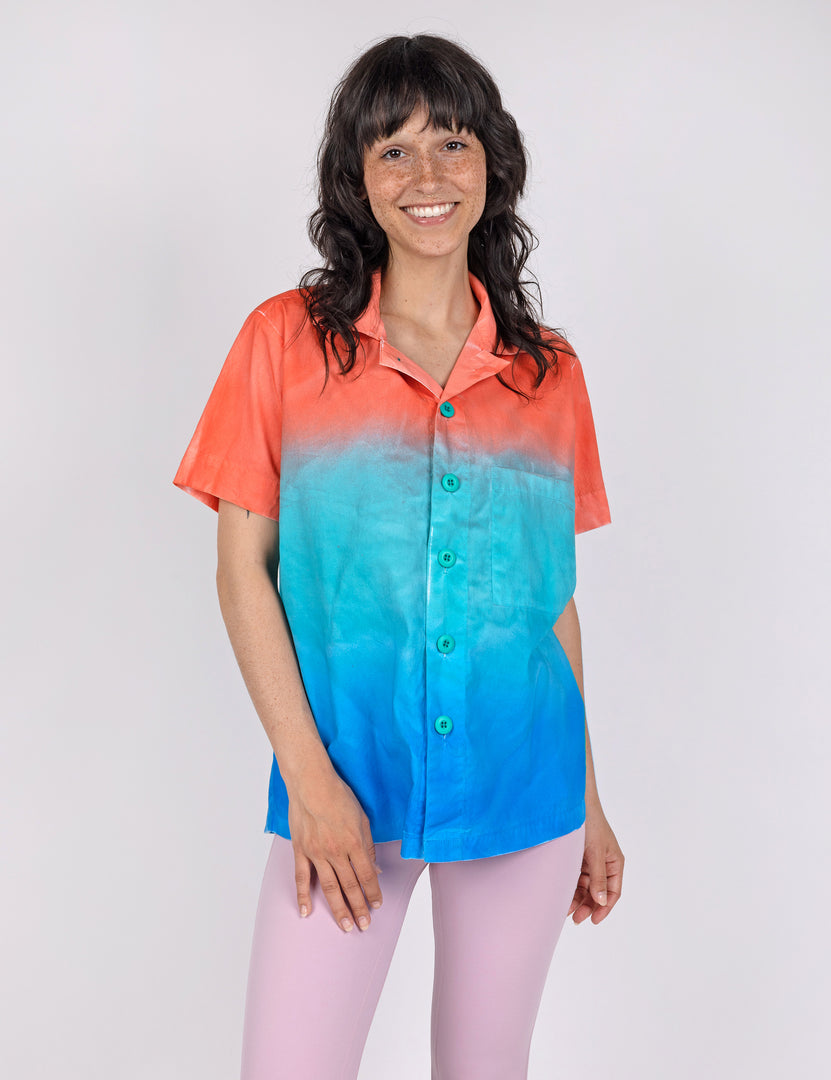 woman wearing a button down shirt in gradient designs of red teal and blue.