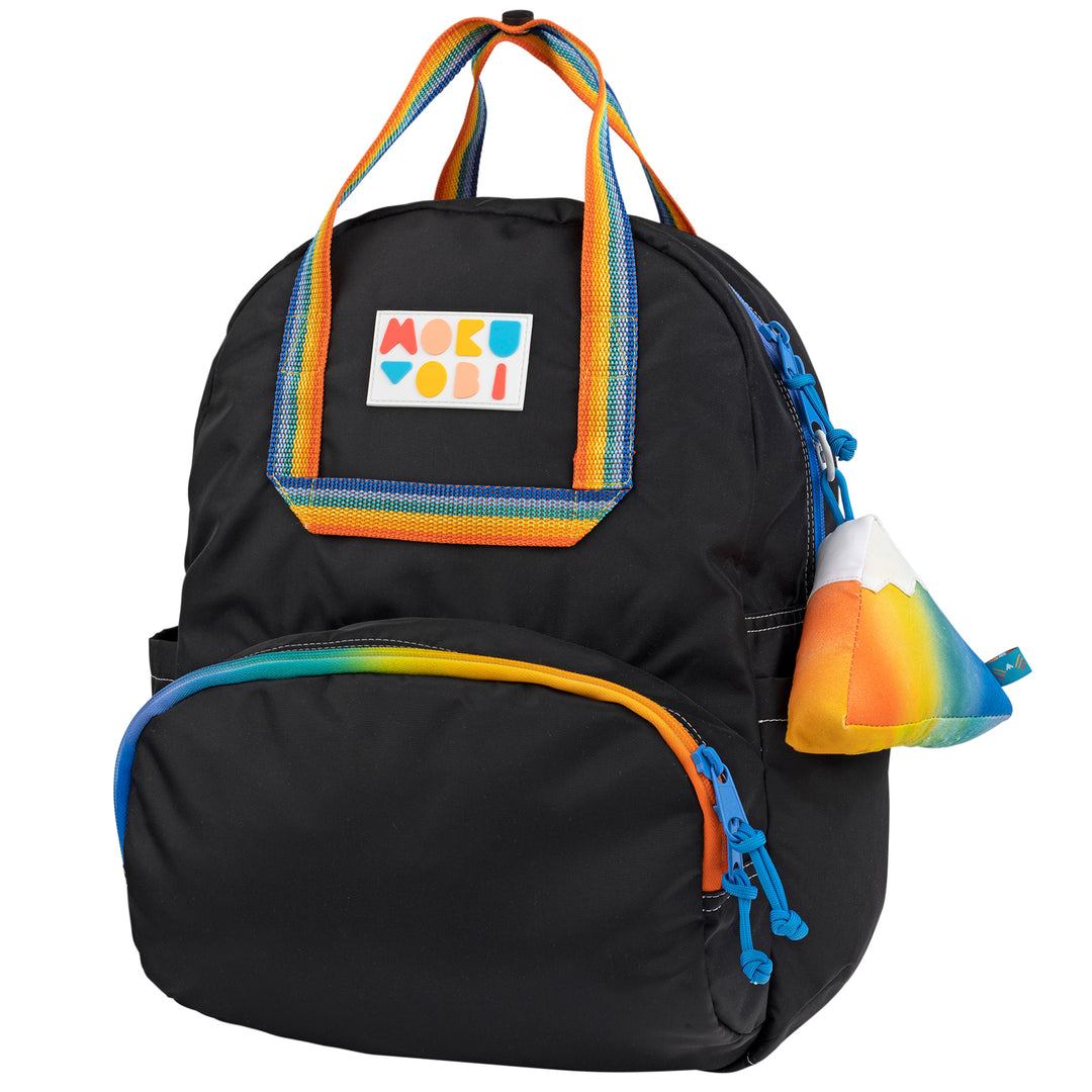 A solid colored backpack with a mountain keychain accessory